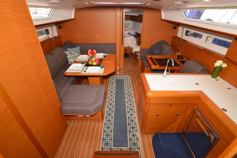 Slide: The Image of 2014 Jeanneau Sun Odyssey 469 sailboat docked at marina, featuring blue canopy and sleek design. - 13