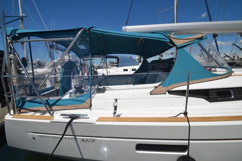 Slide: The Image of 2014 Jeanneau Sun Odyssey 469 docked in a marina with palm trees and clear blue sky. - 2