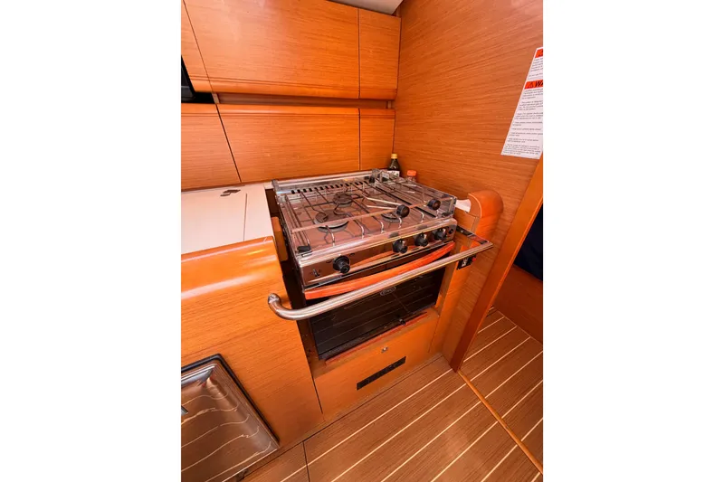 Slide: The Image of 2014 Jeanneau Sun Odyssey 469 yacht kitchen with stove and wooden cabinetry. - 52