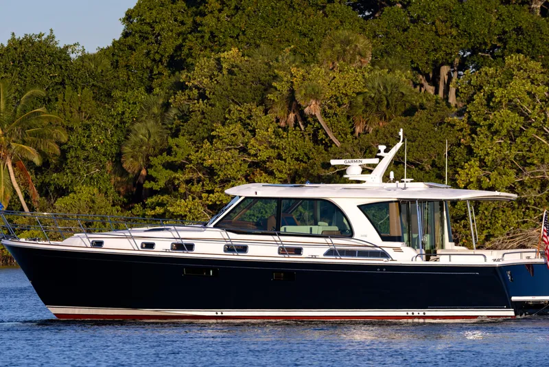 Slide: The Image of 2026 Sabre 51 Salon Express yacht cruising on a serene waterway with lush greenery. - 3