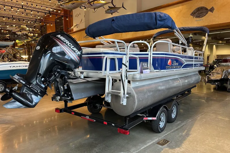 Slide: The Image of 2015 Sun Tracker Fishin' Barge 22 DLX pontoon boat with Mercury outboard motor in showroom. - 2