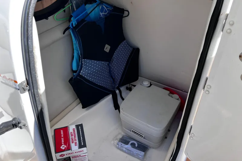 Slide: The Image of 2005 Chaparral Sunesta 254 storage area with life jacket, portable toilet, and fire extinguisher. - 10