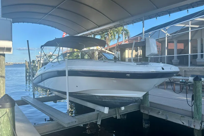Slide: The Image of 2019 Hurricane SunDeck 2690 OB boat docked under canopy by waterfront home. - 0