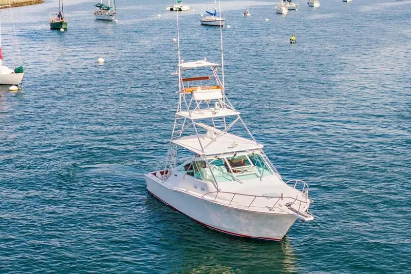 Slide: The Image of 2005 Cabo 35 Express boat cruising in a scenic harbor with other vessels. - 25