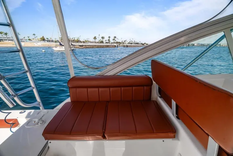 Slide: The Image of 2005 Cabo 35 Express boat interior with brown seating, ocean view, and clear sky. - 48