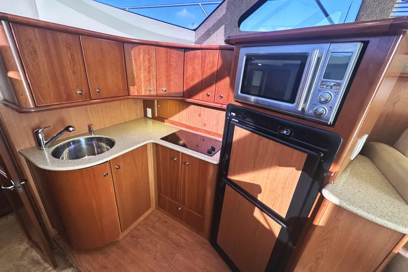 Slide: The Image of 2008 Silverton 36 Convertible yacht kitchen with wood cabinets, sink, microwave, and fridge. - 13