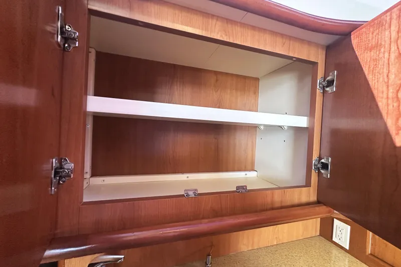 Slide: The Image of Open wooden cabinet with shelves inside a 2008 Silverton 36 Convertible boat. - 17