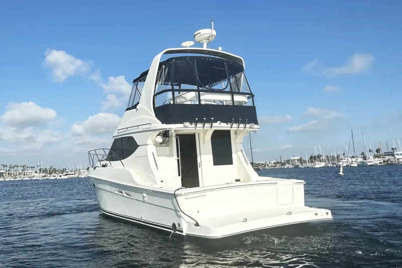 Slide: The Image of 2008 Silverton 36 Convertible yacht cruising in a marina under a clear blue sky. - 3
