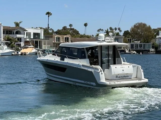 Slide: The Image of 2013 Jeanneau NC11 boat cruising in a scenic waterfront area with modern homes. - 18