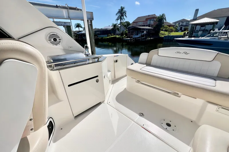 Slide: The Image of 2012 Sea Ray 310 Sundancer boat interior with seating and storage, docked by waterfront homes. - 12