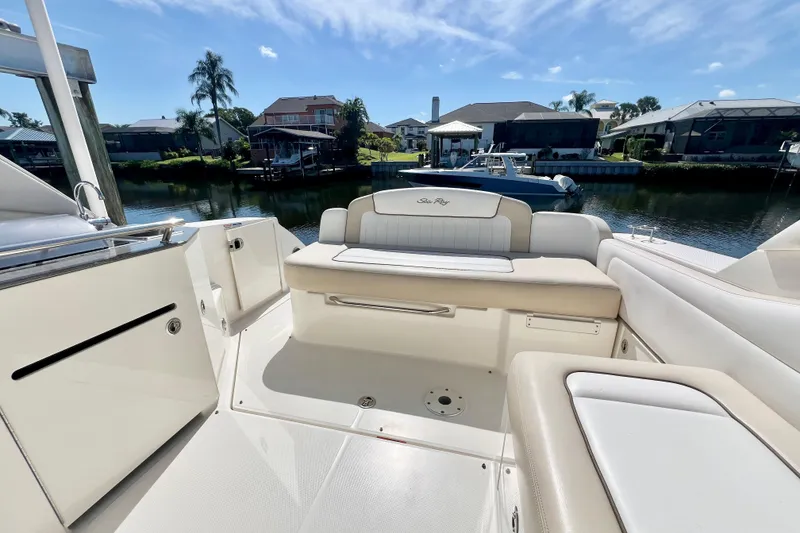 Slide: The Image of 2012 Sea Ray 310 Sundancer boat interior with seating, docked by waterfront homes. - 13