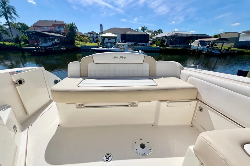 Slide: The Image of 2012 Sea Ray 310 Sundancer boat interior with beige seating, docked by waterfront homes. - 14