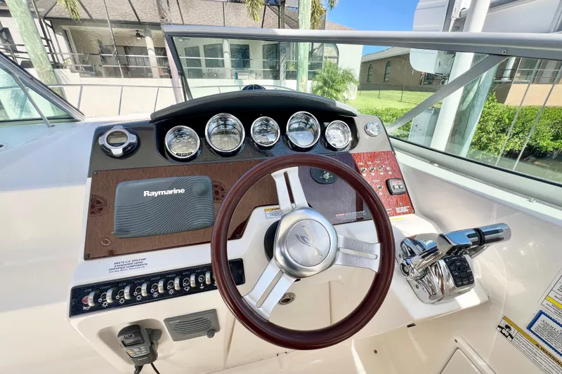 Slide: The Image of 2012 Sea Ray 310 Sundancer helm with Raymarine navigation and classic wood accents. - 18