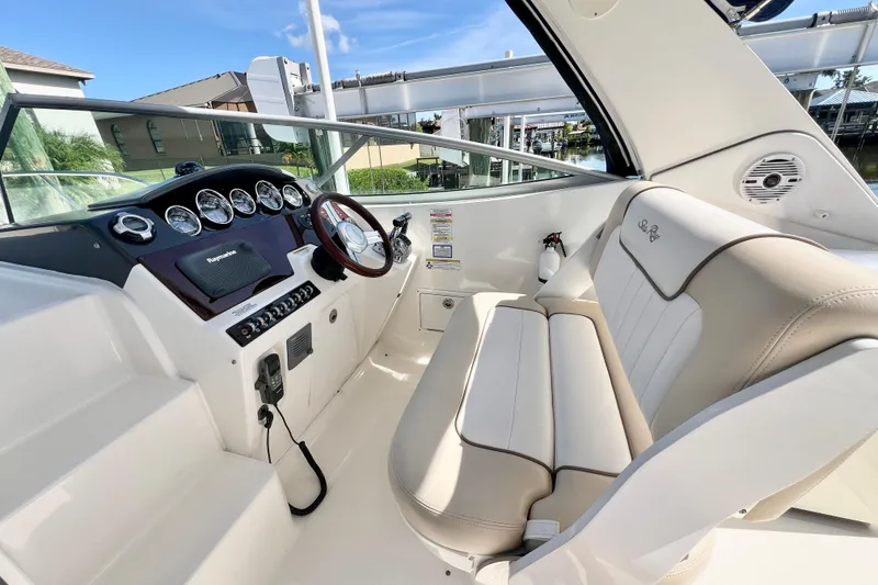 Slide: The Image of 2012 Sea Ray 310 Sundancer helm with beige seating and modern dashboard controls. - 2