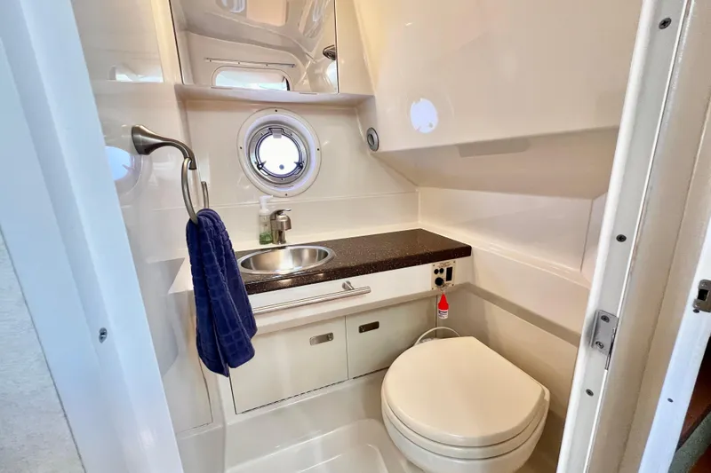 Slide: The Image of 2012 Sea Ray 310 Sundancer bathroom with sink, toilet, and porthole window. - 25