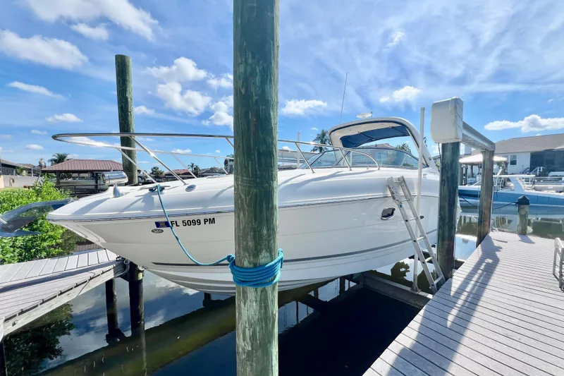 Slide: The Image of 2012 Sea Ray 310 Sundancer boat docked under a clear blue sky. - 4