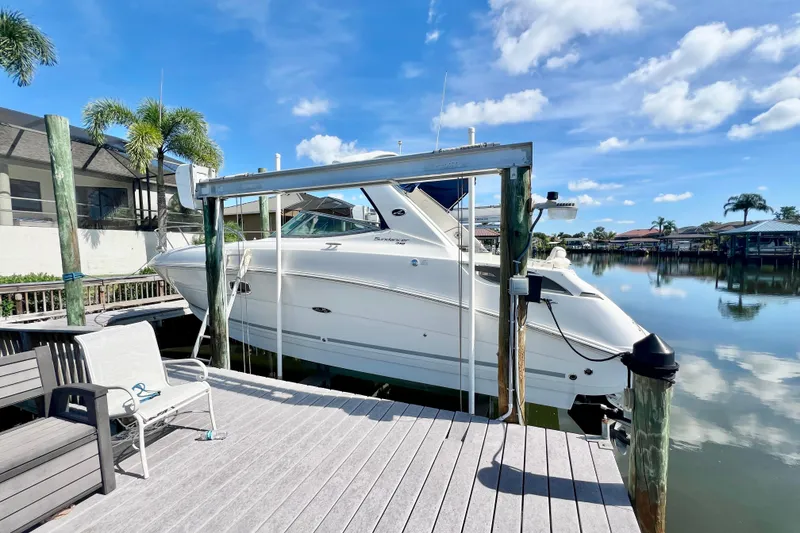 Slide: The Image of 2012 Sea Ray 310 Sundancer docked by a serene waterfront with clear skies. - 5
