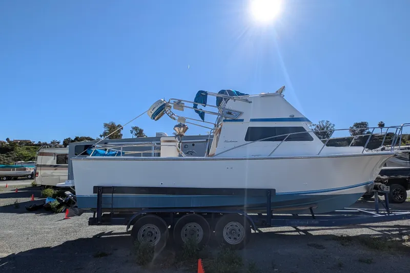Slide: The Image of 1989 Blackman Billfisher 26 boat on trailer under bright sun. - 14