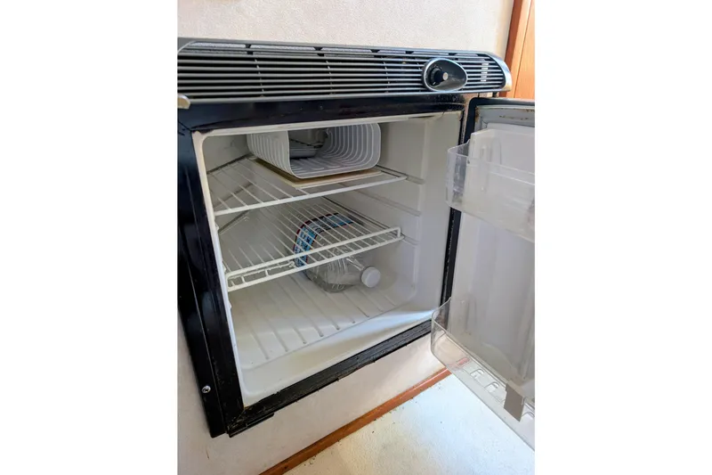 Slide: The Image of Open refrigerator inside 1989 Blackman Billfisher 26 boat, showing shelves and water bottle. - 21