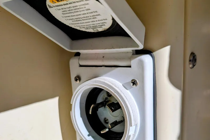 Slide: The Image of 1989 Blackman Billfisher 26 boat power outlet with open cover, showing plug socket. - 28