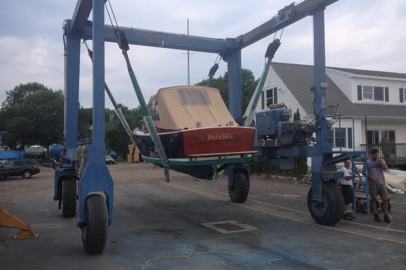 Slide: The Image of 1958 Atkins Sun Flower 22 boat lifted by crane in a shipyard setting. - 10