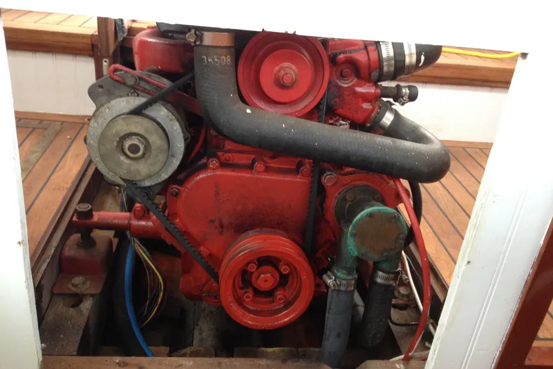 Slide: The Image of 1958 Atkins Sun Flower 22 engine, red with visible belts and hoses, in a wooden compartment. - 13