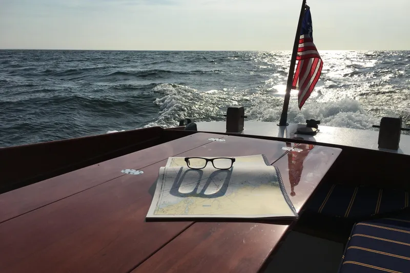 Slide: The Image of Vintage 1958 Atkins Sun Flower 22 boat with map and glasses on deck, American flag waving. - 5