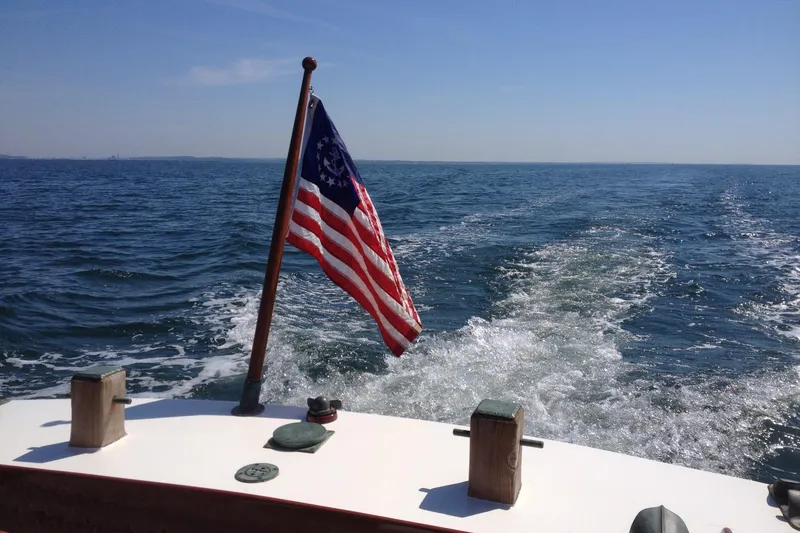 Slide: The Image of Vintage 1958 Atkins Sun Flower 22 boat with American flag on open sea. - 6