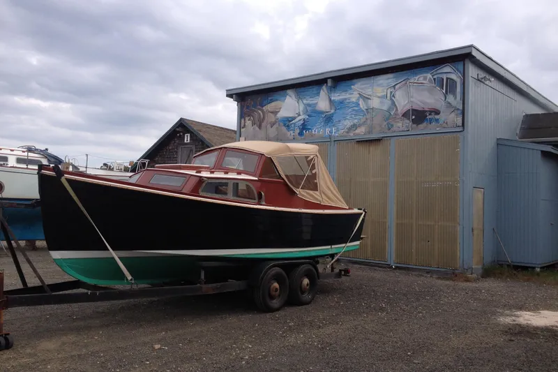 Slide: The Image of 1958 Atkins Sun Flower 22 boat on trailer near a mural-painted building. - 7