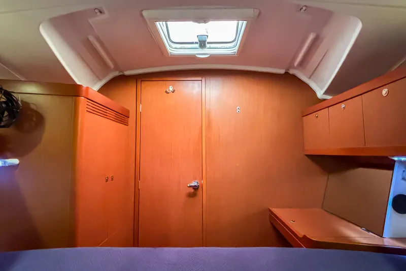 Slide: The Image of Interior cabin of 2015 Beneteau Oceanis 37 sailboat, featuring wood paneling and storage. - 11