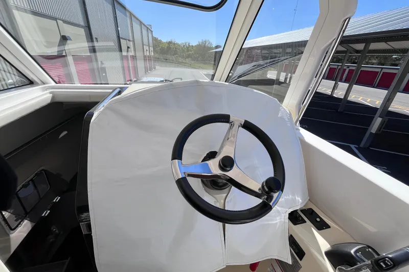 Slide: The Image of 2019 Regal 33 SAV boat helm with steering wheel, docked in a marina. - 15
