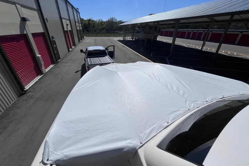 Slide: The Image of Covered 2019 Regal 33 SAV boat near storage units and parked vehicle. - 16