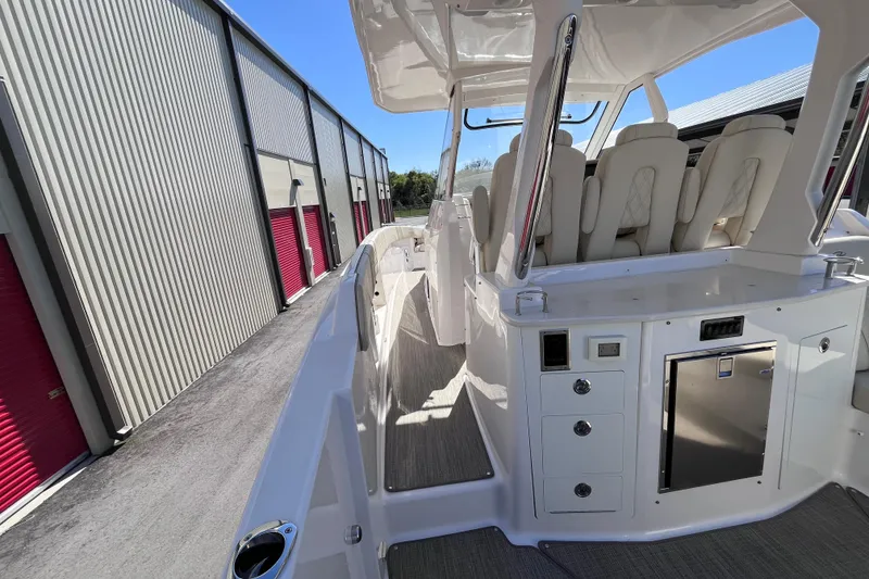 Slide: The Image of 2019 Regal 33 SAV boat interior with seating and storage, docked near storage units. - 22