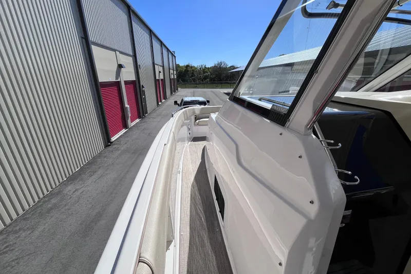 Slide: The Image of 2019 Regal 33 SAV boat docked beside storage units under clear blue sky. - 29