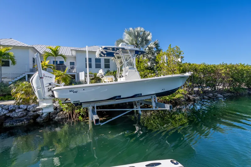 The Image of 2017 SeaVee 270Z boat on lift by waterfront home, clear blue sky. - 1