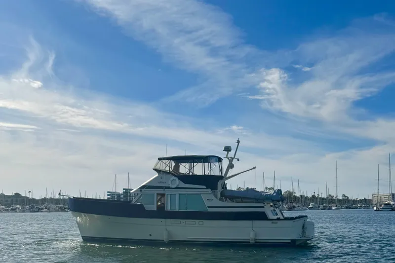 Slide: The Image of 1985 Tollycraft 48 Cockpit Motor Yacht docked in marina, surrounded by sailboats. - 10