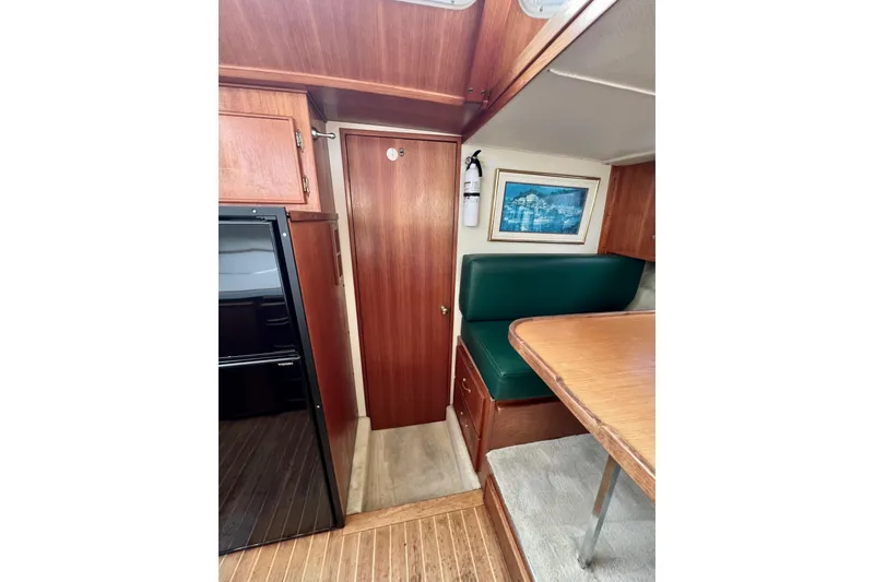Slide: The Image of Interior of 1985 Tollycraft 48 Cockpit Motor Yacht with green cushioned seating and wooden table. - 102