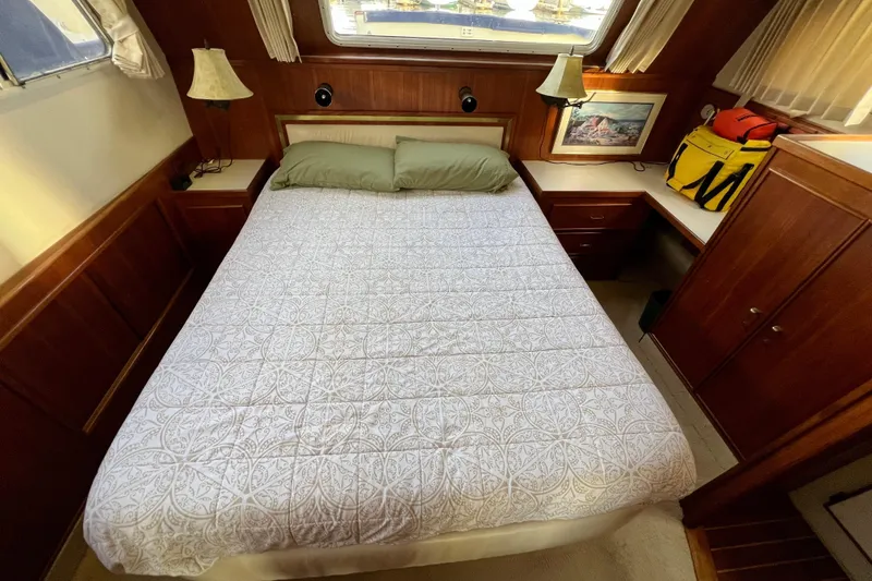 Slide: The Image of 1985 Tollycraft 48 Cockpit Motor Yacht bedroom with cozy bed and wooden interior. - 132