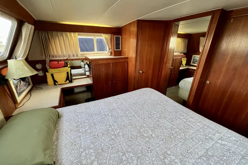 Slide: The Image of 1985 Tollycraft 48 Cockpit Motor Yacht bedroom with bed, wood paneling, and small sink area. - 134