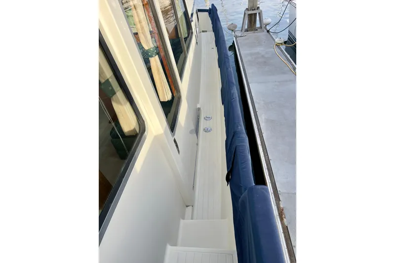 Slide: The Image of 1985 Tollycraft 48 Cockpit Motor Yacht railing with marina background under clear blue sky. - 21