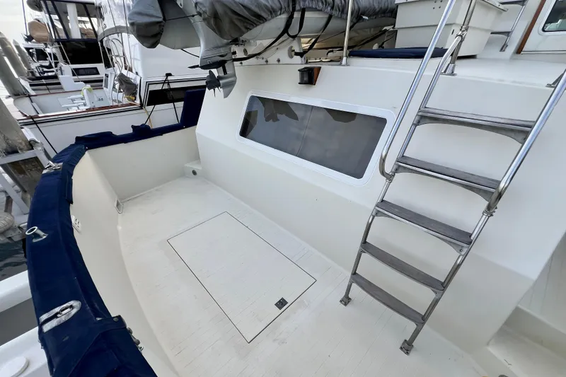 Slide: The Image of 1985 Tollycraft 48 Cockpit Motor Yacht docked, showcasing spacious deck and outboard motor. - 28