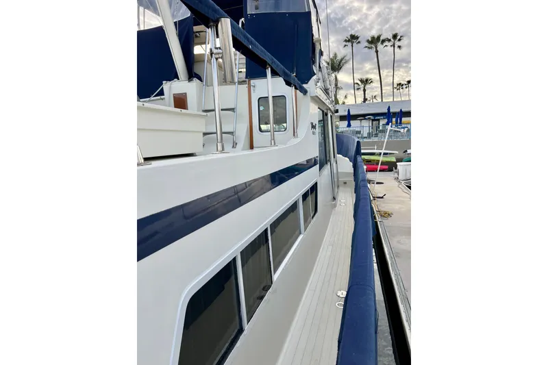 Slide: The Image of 1985 Tollycraft 48 Cockpit Motor Yacht docked, featuring sleek design and blue accents. - 30