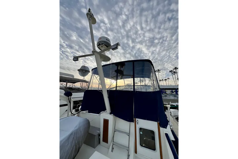 Slide: The Image of 1985 Tollycraft 48 Cockpit Motor Yacht docked, featuring covered equipment and adjacent vessel. - 36