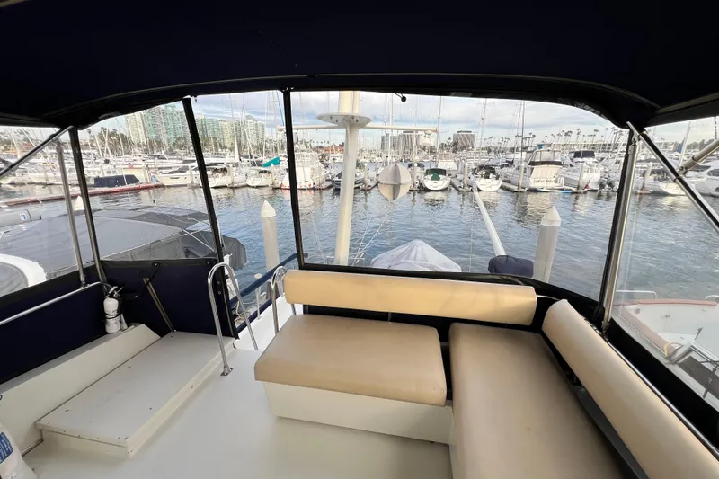 Slide: The Image of 1985 Tollycraft 48 Cockpit Motor Yacht interior with marina view, featuring seating and helm area. - 45