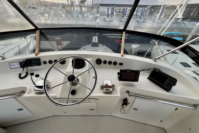 Slide: The Image of 1985 Tollycraft 48 Cockpit Motor Yacht interior with seating and helm, docked at marina. - 47