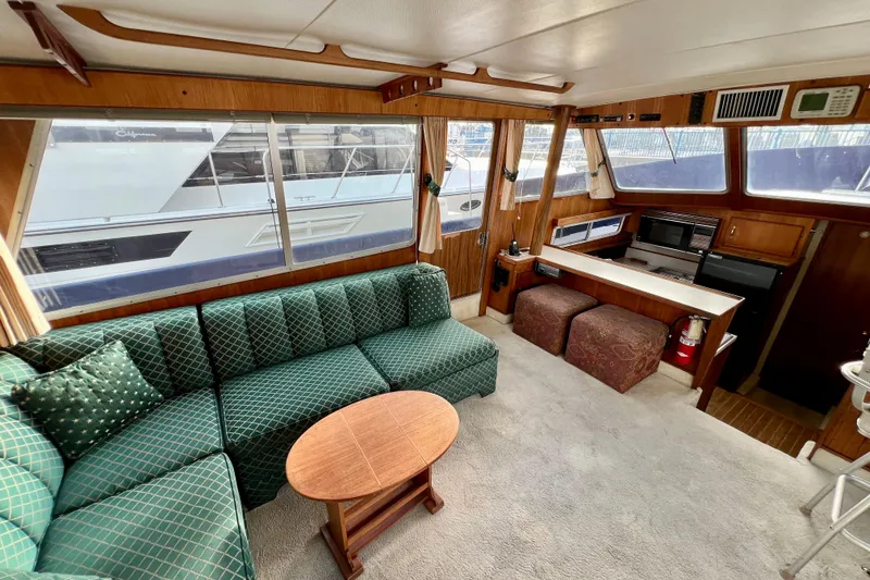 Slide: The Image of Interior of 1985 Tollycraft 48 Cockpit Motor Yacht with green patterned sofa and wooden table. - 61