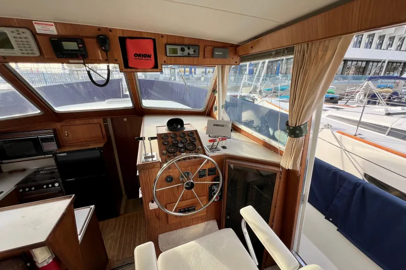 Slide: The Image of 1985 Tollycraft 48 Cockpit Motor Yacht interior with helm, navigation equipment, and seating area. - 64