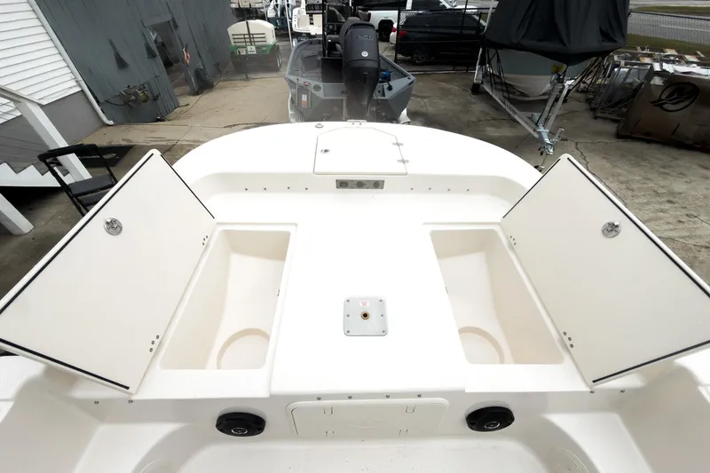 Slide: The Image of 2026 Carolina Skiff 21 LS boat with open storage compartments, docked outdoors. - 26