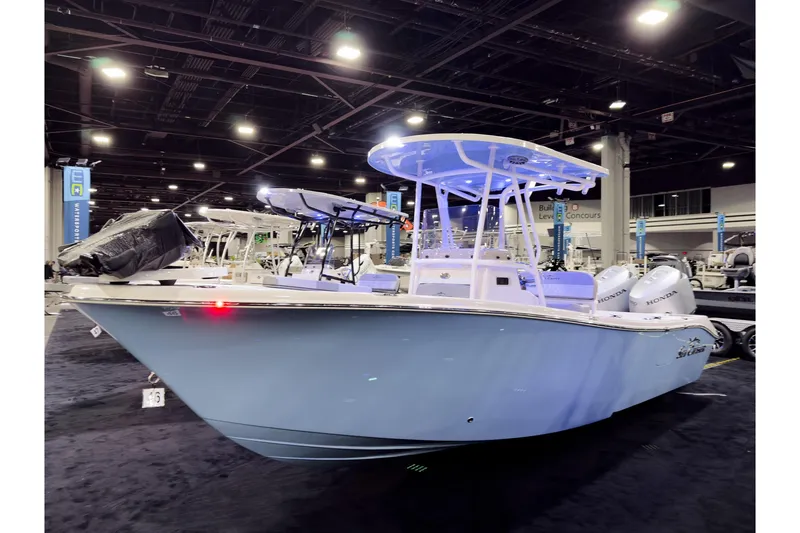 Slide: The Image of 2026 Sea Chaser 24 HFC DE boat displayed indoors with blue lighting and twin Honda engines. - 1