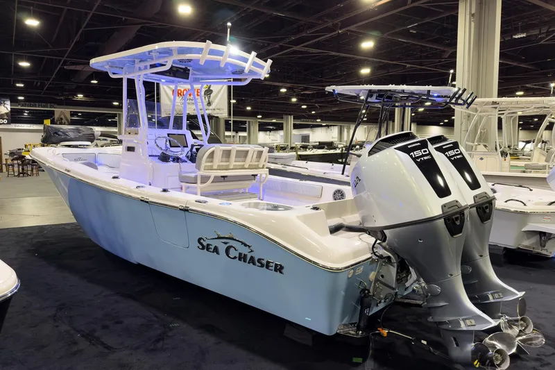 Slide: The Image of 2026 Sea Chaser 24 HFC DE boat with dual Honda 150 engines at indoor exhibit. - 2